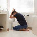 Woman, feeling ill, holding her head over the toilet in the bathroom.