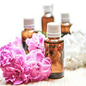 Two bottles of essential oils arranged near purple and white flowers.